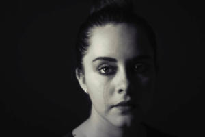 Foto em preto e branco aproximada do rosto de uma mulher chorando