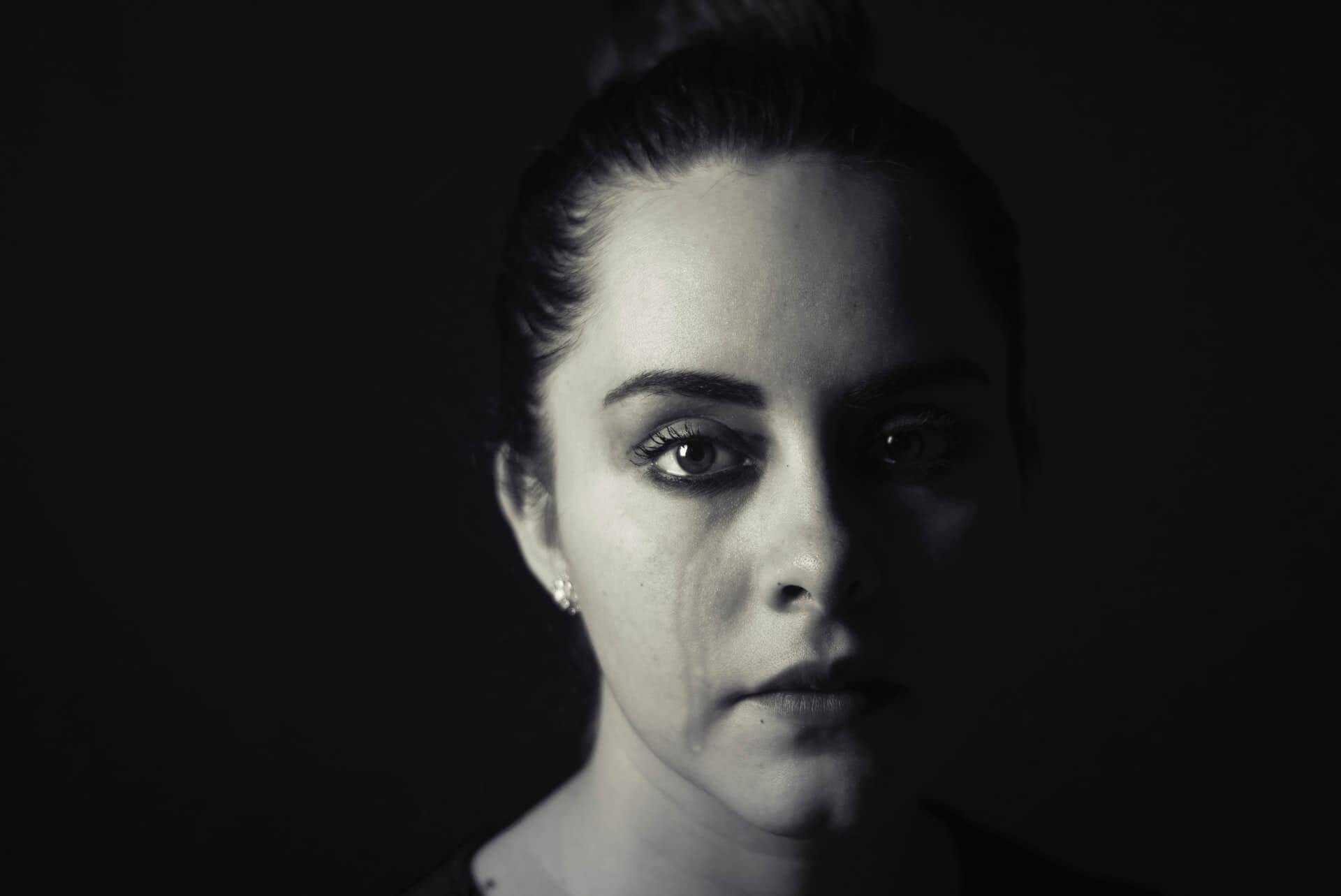 Foto em preto e branco aproximada do rosto de uma mulher chorando