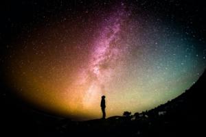 Foto grande angular da silhueta de uma pessoa observando um céu muito estrelado