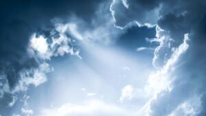 Foto de um céu azul nublado com a luz do sol atravessando as nuvens