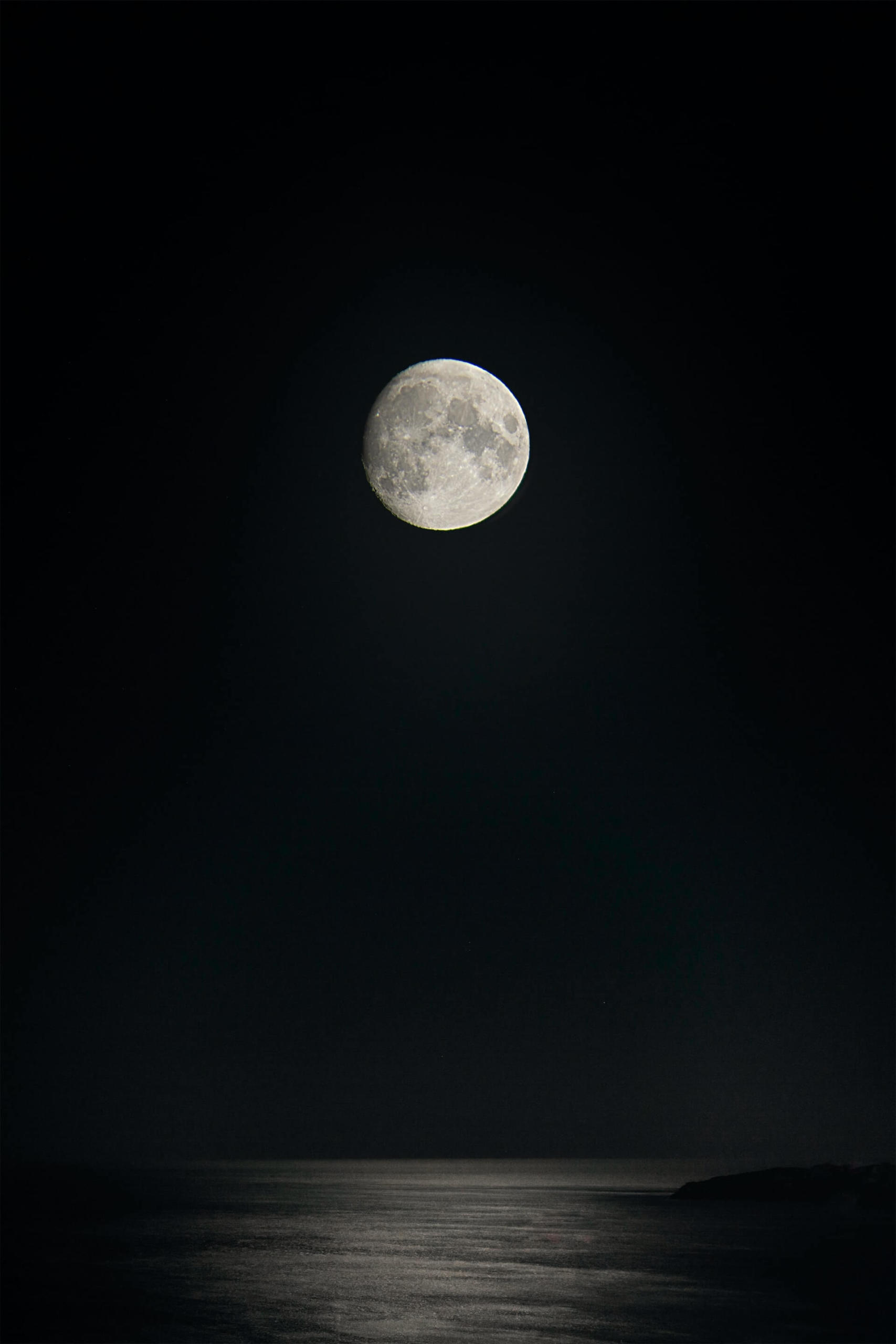 Foto de lua cheia acinzentada sobre o mar calmo